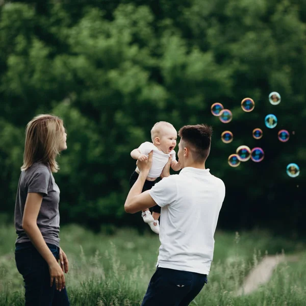 Famille jouant à l'extérieur, soufflant des bulles de savon . — Photo