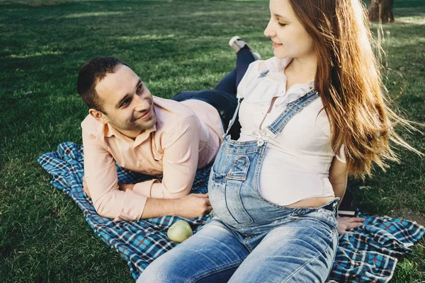 Беременная пара наслаждается временем вместе в парке — стоковое фото