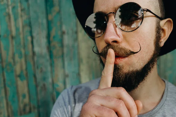 Hipster man gesture for silence showing hush sign