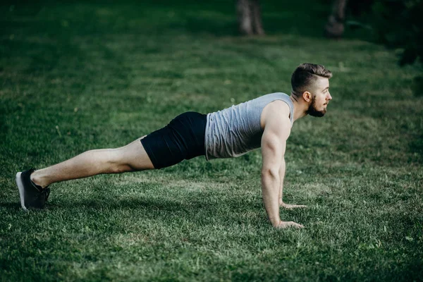 Young fit muscular man doing plank outdoors — Stock Photo, Image