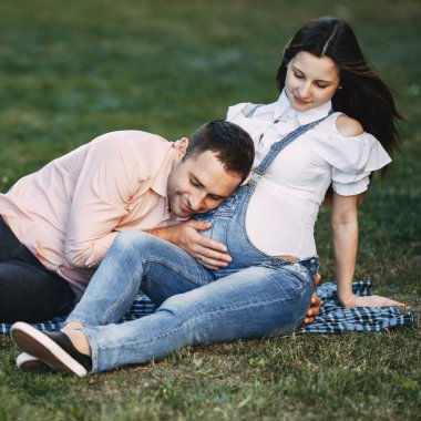 Babası müstakbel karın içinde hareketli bebek dinleme. Hamile çift doğada sarılma. Mutluluk, aşk, Aile kavramı