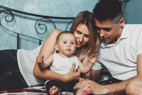 Genitori con bambina seduta sul letto di casa — Foto Stock