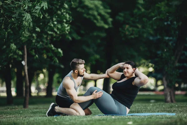 Mujer de talla grande haciendo ejercicio con entrenador personal — Foto de Stock