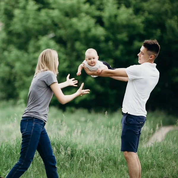 Gelukkige ouders spelen met baby dochter outdoors — Stockfoto