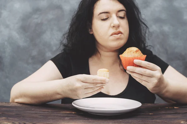Donna obesa che sceglie tra piccolo e grande muffin — Foto Stock