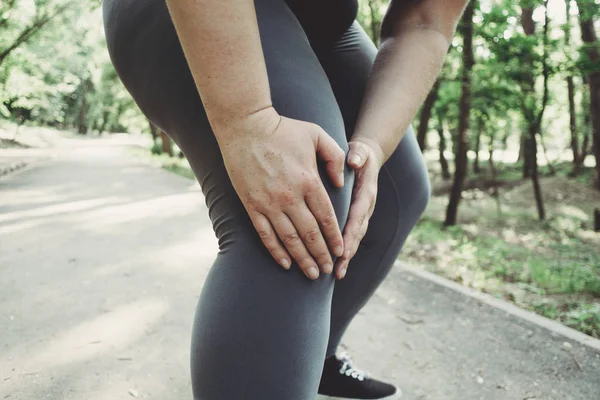 Mujer tocándose la pierna, tiene un trauma en la rodilla al correr al aire libre . —  Fotos de Stock