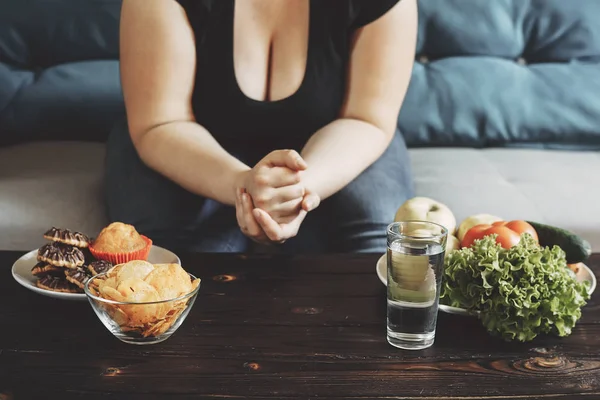 Mulher obesa escolhendo entre comida saudável e junk — Fotografia de Stock