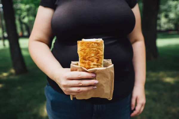 Mulher com excesso de peso come burrito andando ao ar livre — Fotografia de Stock