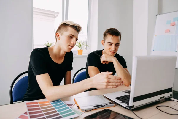 Двоє молодих чоловіків, які дивляться на монітор ноутбука обговорюють — стокове фото