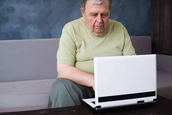 Äldre man som arbetar på laptop i vardagsrum — Stockfoto