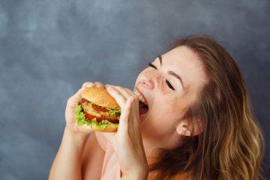 Genç kadın tadı zevk hamburger yemek