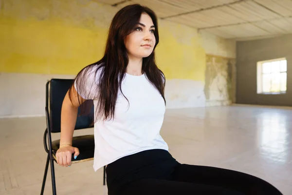 Kadın sandalyede eğilerek fiziksel egzersiz yaparak — Stok fotoğraf