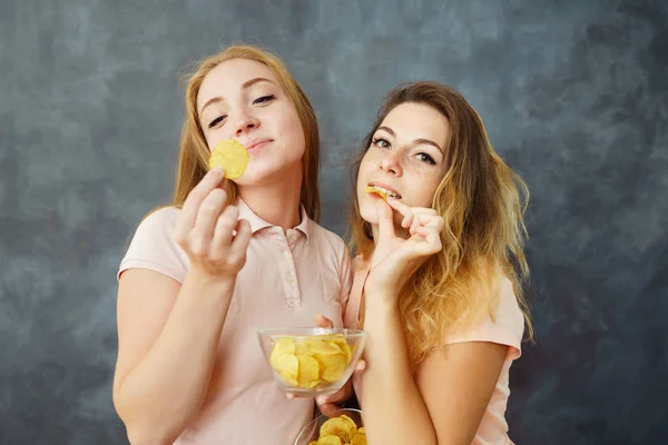 Dos mujeres jóvenes comiendo papas fritas codiciosamente —  Fotos de Stock