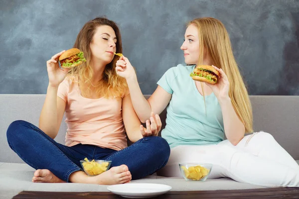 Mulheres jovens sentadas no ônibus comer hambúrgueres — Fotografia de Stock