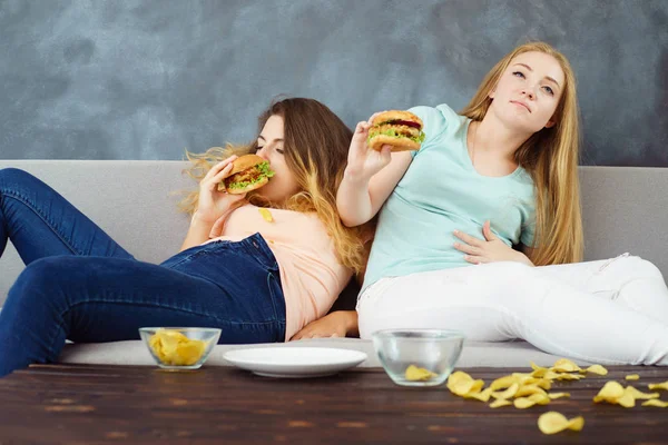 Mulheres superestimadas sentadas com lotes de fast-food — Fotografia de Stock