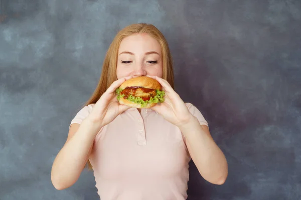 Mujer joven comiendo hamburguesa deliciosamente deliciosa —  Fotos de Stock