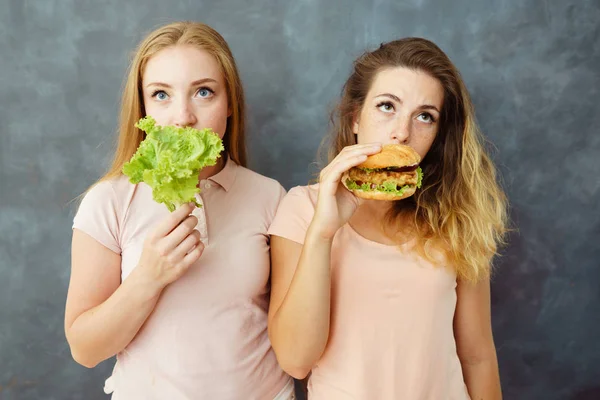 Salata ve hamburger olan iki genç kadın