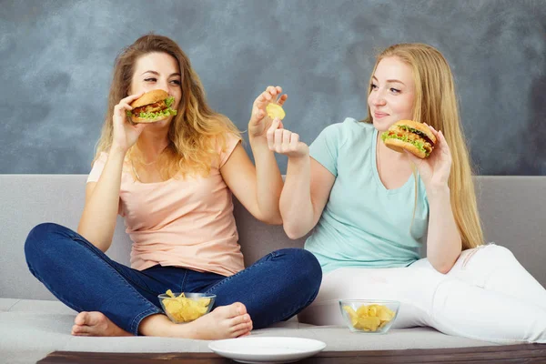 Due donne sedute al coach che mangiano fast food — Foto Stock