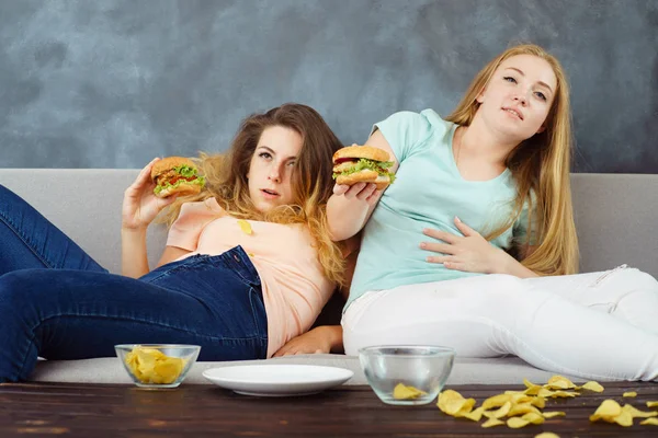 Donne mangiate troppo sdraiato a allenatore mangiare fast food — Foto Stock