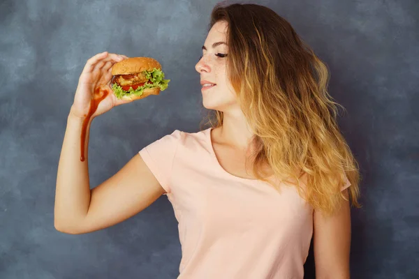 Mujer joven luchando contra la tentación de comer hamburguesa —  Fotos de Stock