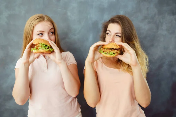 Duas mulheres a comer hambúrgueres e a olhar uma para a outra — Fotografia de Stock