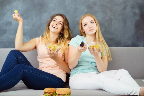 Молоді жінки з телевізором віддалено їдять фаст-фуди — стокове фото