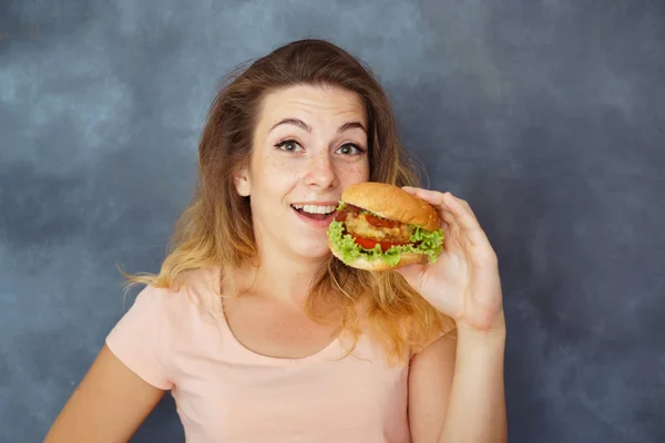 Mujer joven con hamburguesa en las manos disfrutando de la comida —  Fotos de Stock