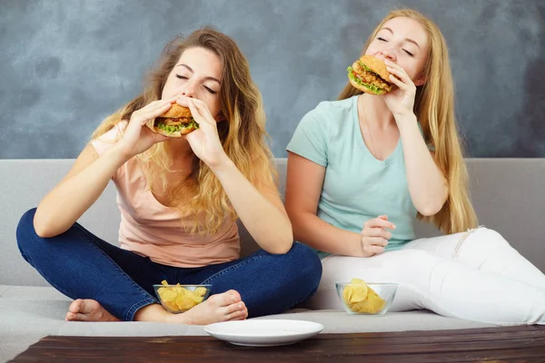 Zwei junge Frauen sitzen am Bus und essen Fast Food — Stockfoto