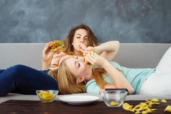 Mulheres superestimadas deitadas no ônibus comendo fast food — Fotografia de Stock