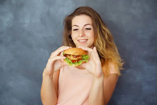 Mujer joven con hamburguesa en las manos disfrutando de la comida —  Fotos de Stock