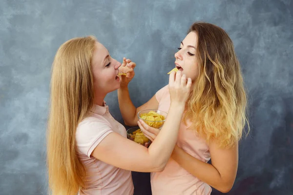 Mignonnes jeunes femmes se nourrissant mutuellement avec des croustilles — Photo