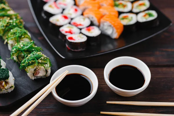 assortment of sushi rolls served on black plate