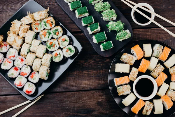 Суши-роллы на черных тарелках, плоский уголок — стоковое фото