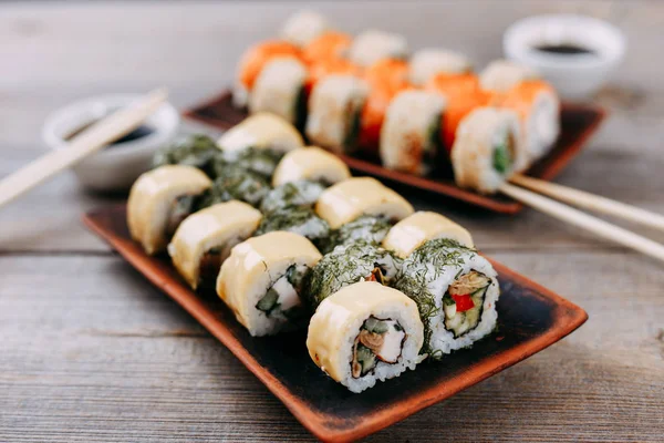 Japanese sushi rolls set served on clay trays — Stock Photo, Image