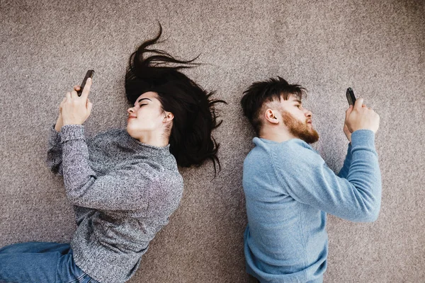 Casal com telefones na sala de estar — Fotografia de Stock