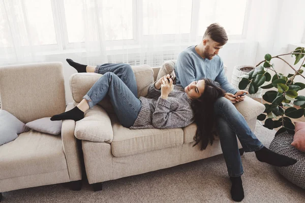 Pareja en sala de estar con teléfonos inteligentes — Foto de Stock