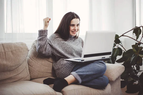 Fiatal nő használ laptop nappaliban izgatott — Stock Fotó