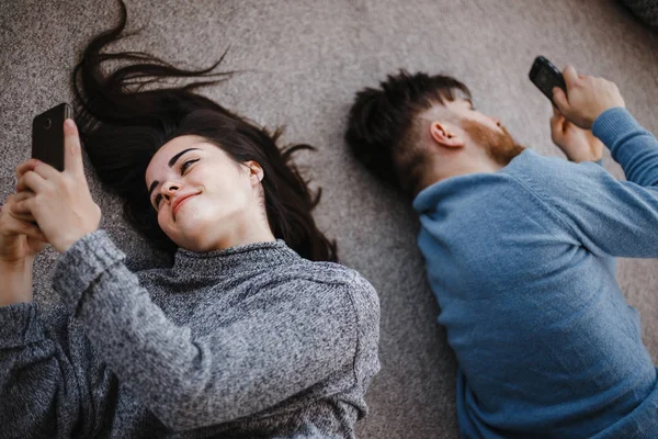 Couple in living room using smart phones