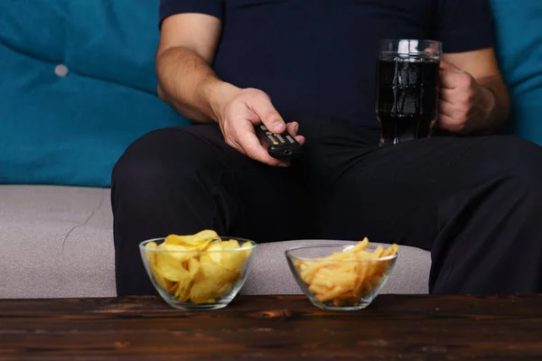 Hombre con sobrepeso con control remoto de televisión, comida chatarra y cerveza — Foto de Stock