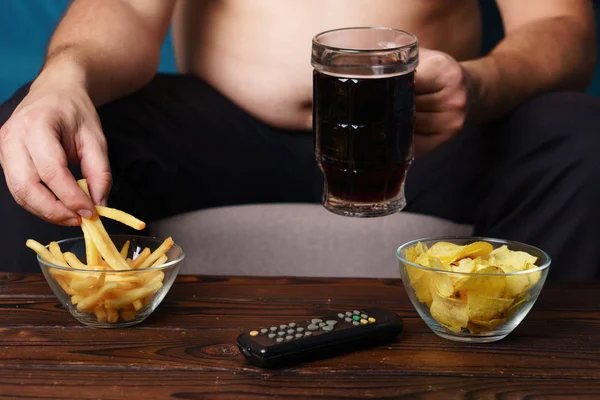 テレビのリモコンがソファの上に座って過食の人 — ストック写真