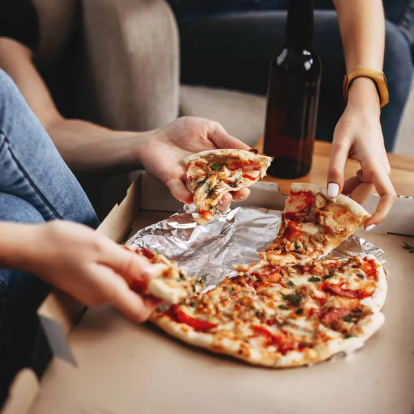 Hands of young people taking pizza slices