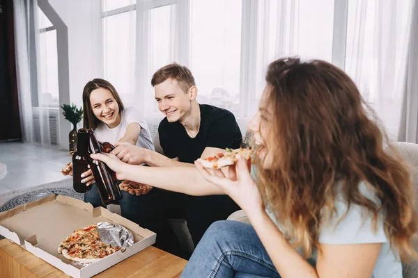friends eat pizza and drink beer, clinking bottles
