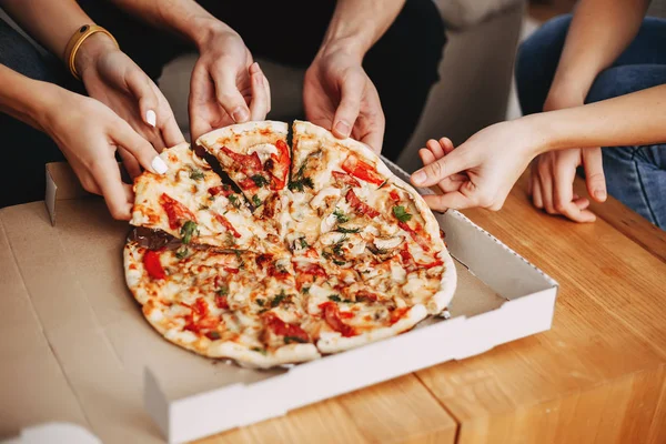 Pizza dilimleri alan genç insanlar ellerini