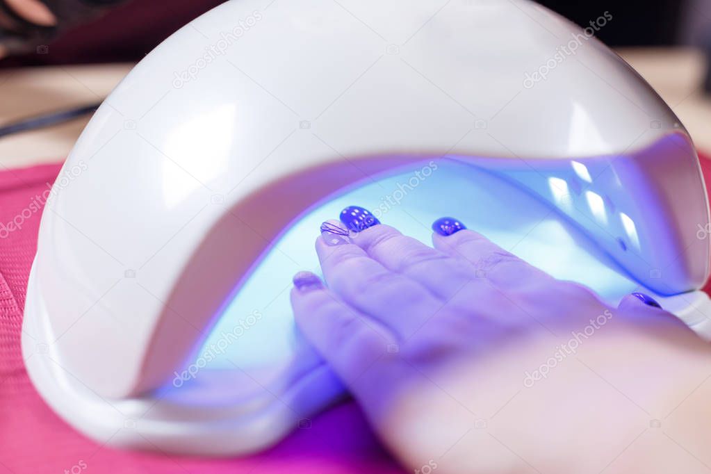 Manicured nails in UV lamp. Rays cure gel polish