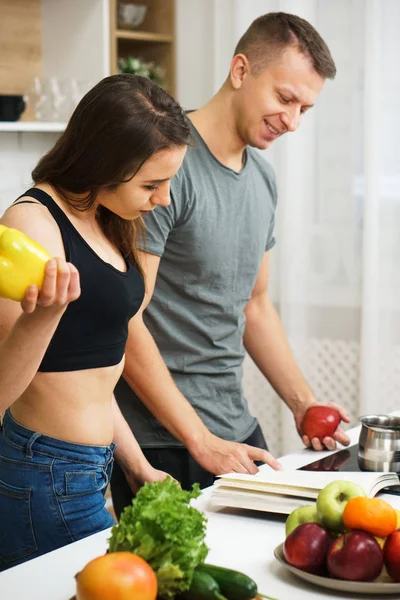 Ajuste pareja delgada lectura receta libro antes de cocinar —  Fotos de Stock