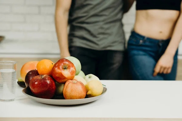 Fit couple snacking with fresh fruits at kitchen — Stock Photo, Image