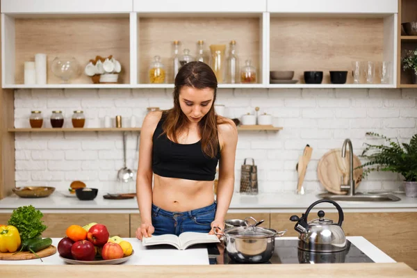 Fit slim woman reading recipe book before cooking — Stock Photo, Image