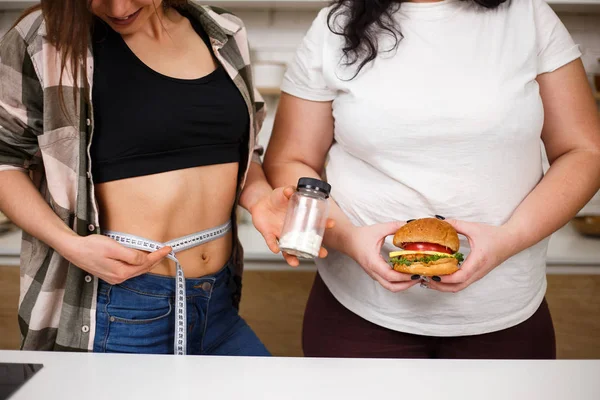 Mulher com sobrepeso com hambúrguer e pílulas de dieta oferecer — Fotografia de Stock
