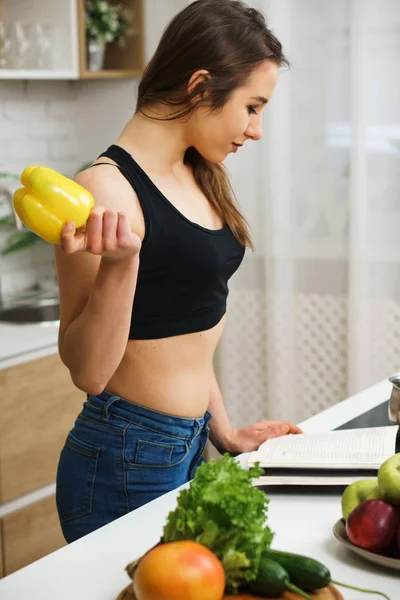 Fit slim woman in sporting top reading recipe book — Stock Photo, Image