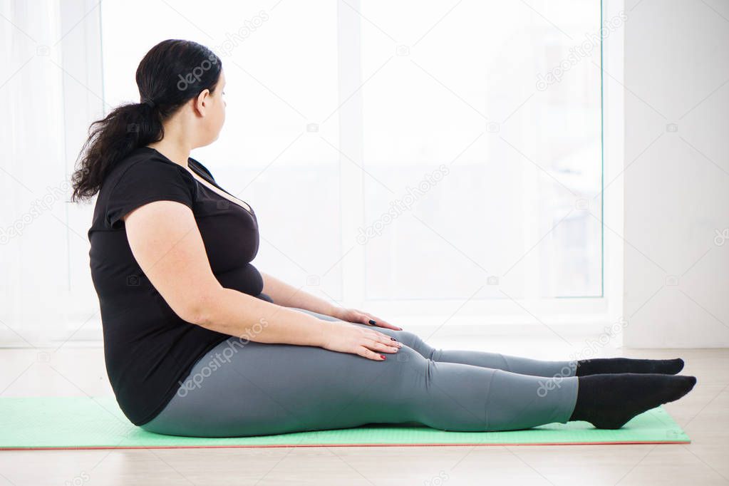 obese woman taking a break between exercise sets
